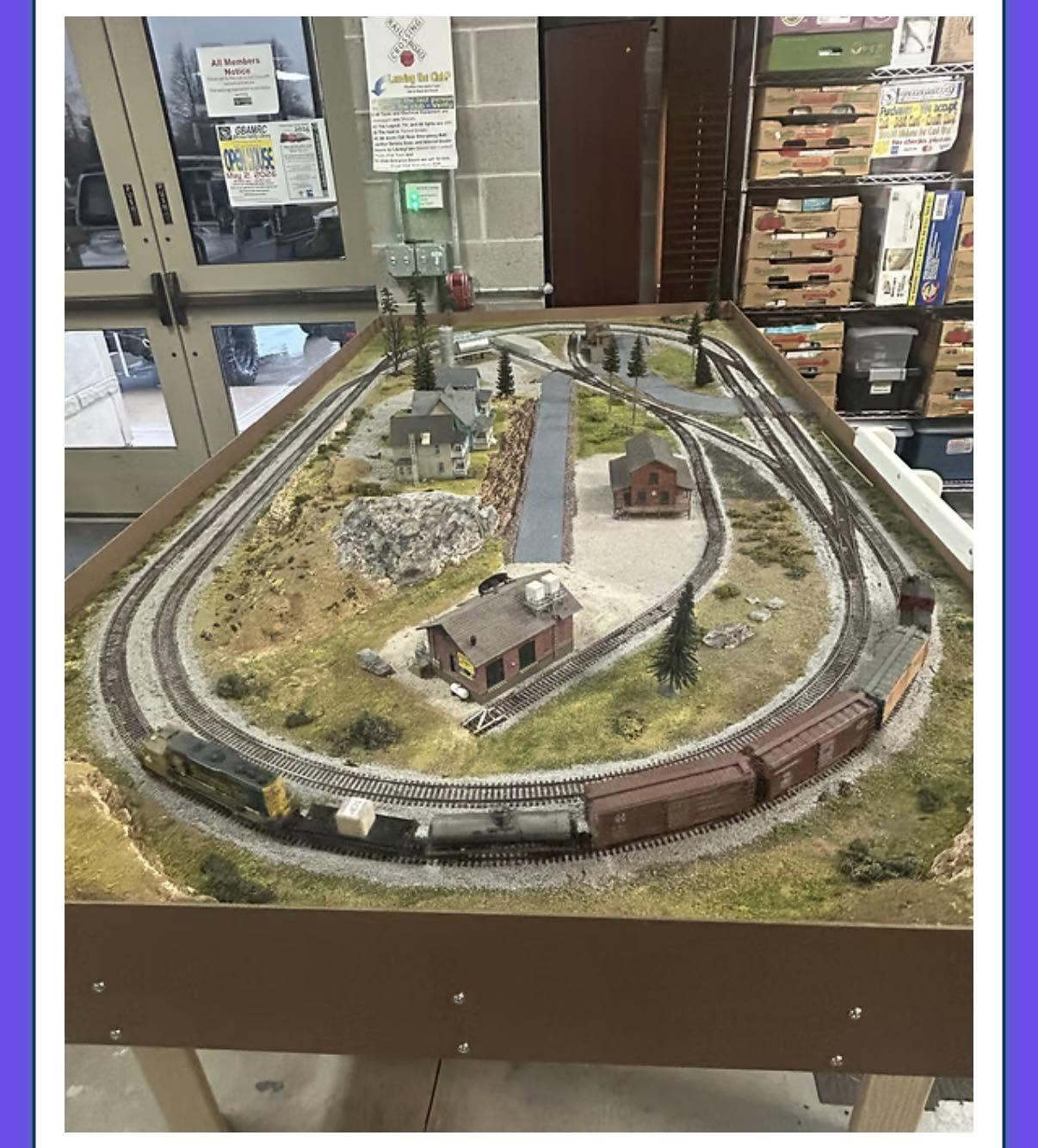 Model railroad raffle layout with locomotive, freight cars, buildings and scenery