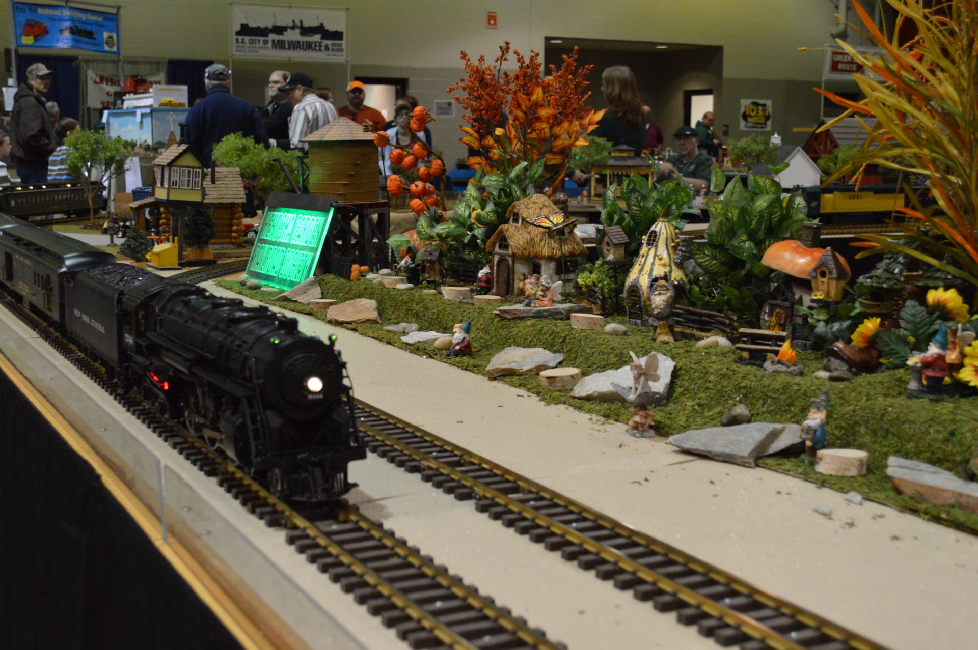 Steam locomotive beside a garden railroad scene